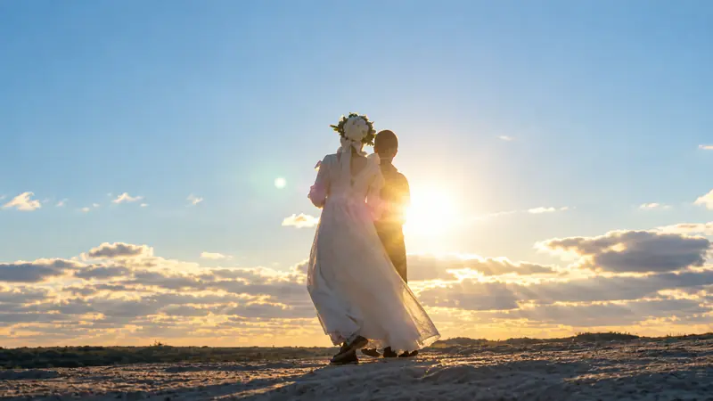 A bride and groom walking together on a dune